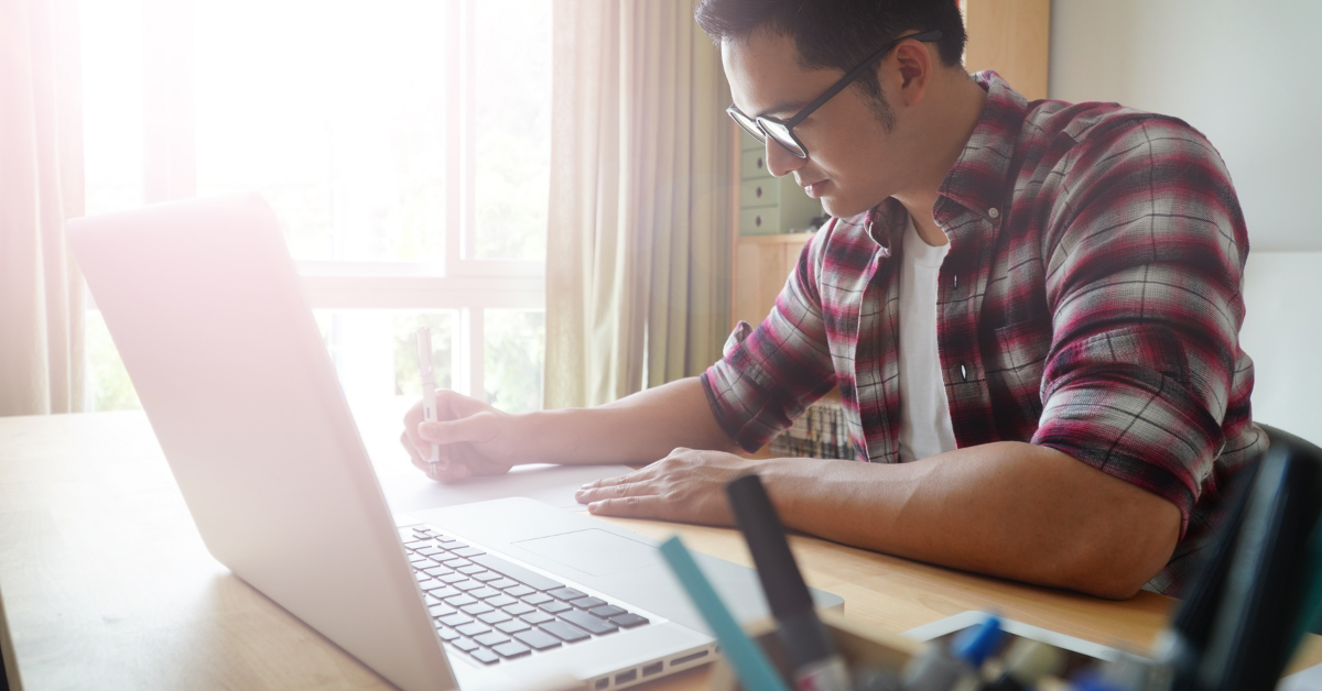 male sitting at desk and laptop studying